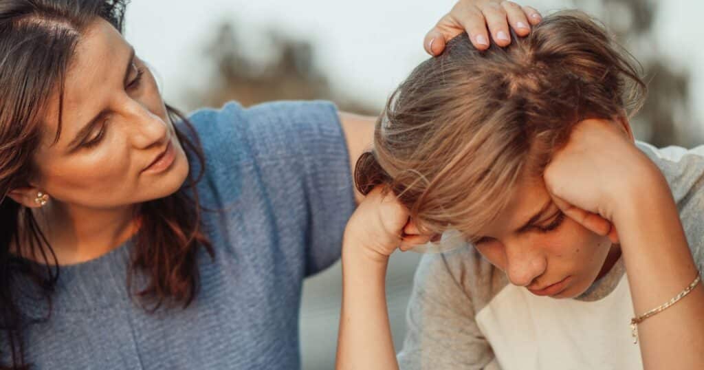 Mother comforting her teenage daughter, resting a hand on her head